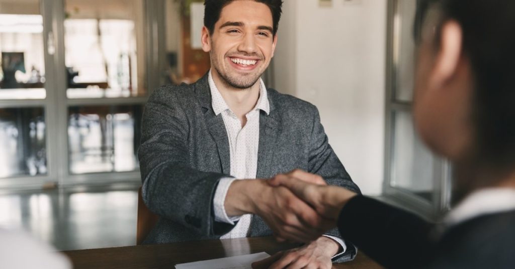 man with resume shaking hands during engineering interview